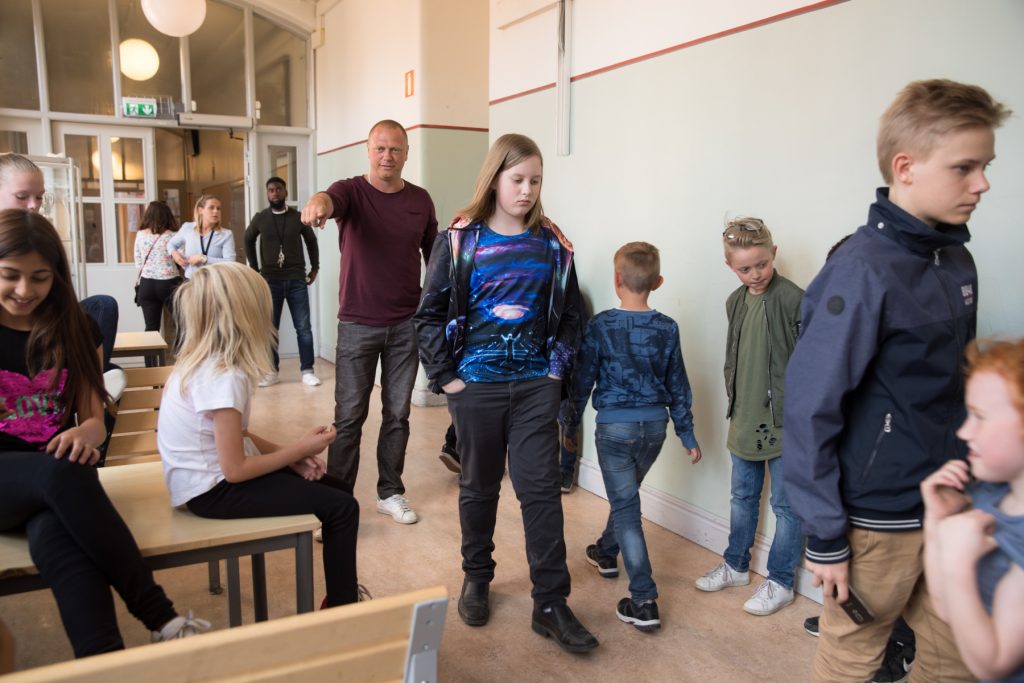 Barn och vuxna rör sig i en skolkorridor