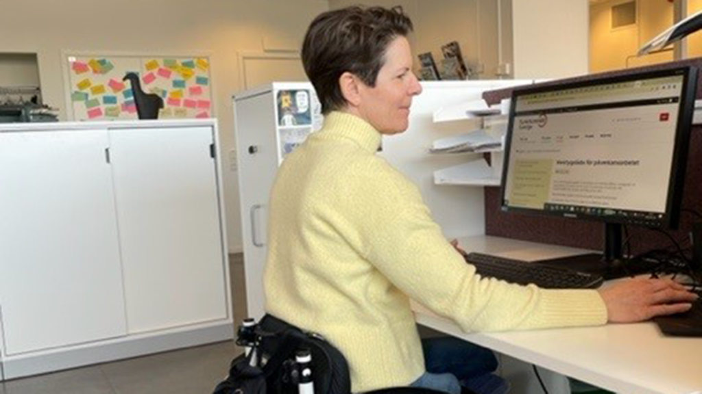 Bilden visar en kvinna som sitter och arbetar vid datorn