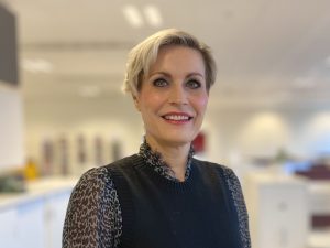Kvinna som tittar in i kameran i kontorslandskap