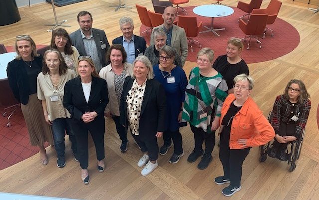 Ett tjugotal personer samlade för gemensamt foto i en stor konferenslokal.