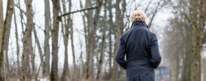 En kvinna går i skogsmiljö med ryggen vänd mot betraktaren