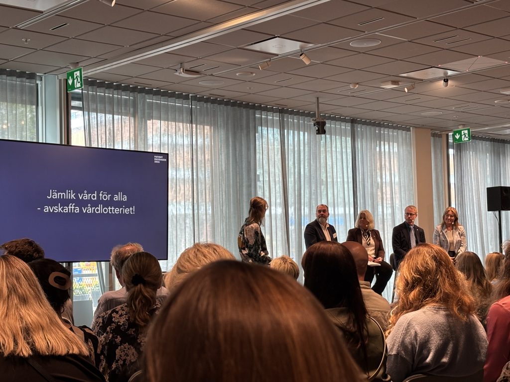 En lokal fylld med människor och en panel längst fram med personer som samtalar