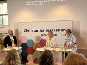 Tre personer diskuterar framme på scenen med texten Civilsamhällesarenan bakom dem