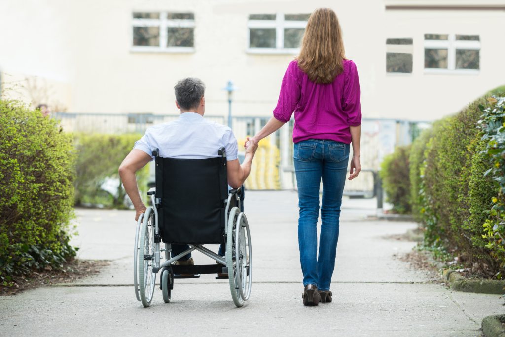 Kvinna går bredvid en man som använder rullstol