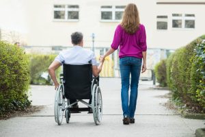 Kvinna går bredvid en man som använder rullstol